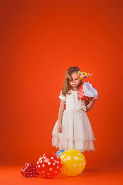 Chica con regalos y globos sobre un fondo naranja . —  Fotos de Stock