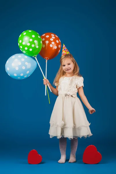 Meisje met geschenken en ballonnen op de blauwe achtergrond. — Stockfoto