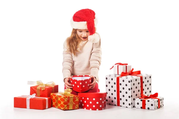 Cute girl in santa claus hat opens christmas presents — Stock Photo, Image