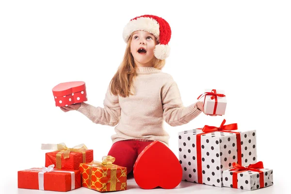 Cute girl in santa claus hat opens christmas presents — Stock Photo, Image