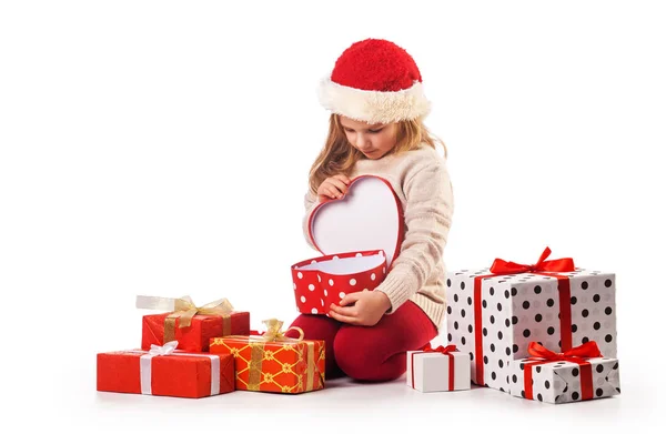 Cute girl in santa claus hat opens christmas presents — Stock Photo, Image