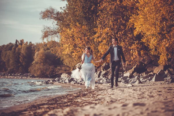 Nowożeńcy spacerują po jesiennej plaży — Zdjęcie stockowe