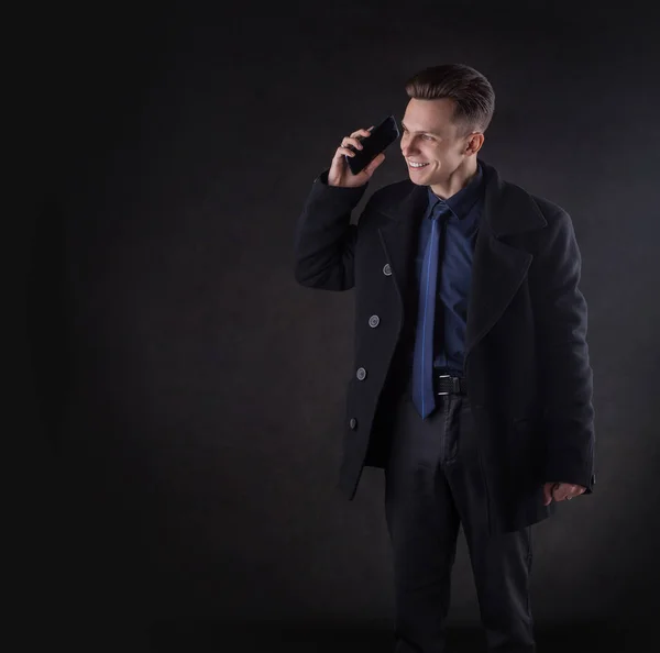 Een knappe man met een jas aan de telefoon.. — Stockfoto