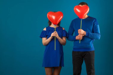 Kırmızı balonlu mavi arka planda aşık genç bir çift..