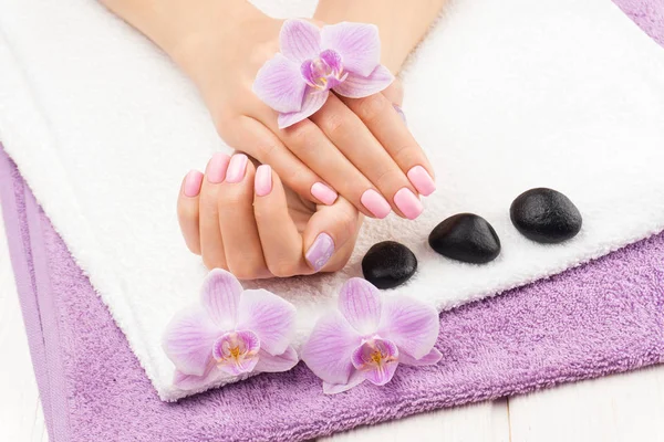 Mooie roze manicure met orchidee, en handdoek op de witte houten tafel. — Stockfoto