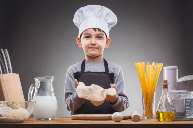 Aşçı çocuk Gri arka planda yemek pişiriyor.