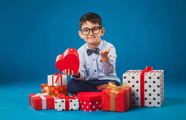 Симпатичный ребенок с подарками на синем фоне — стоковое фото