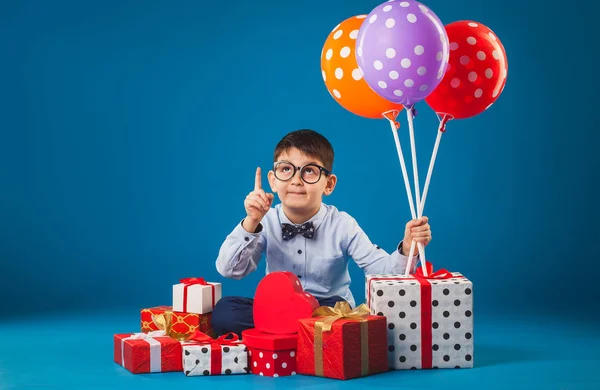 Roztomilé dítě s dárky na modrém pozadí — Stock fotografie