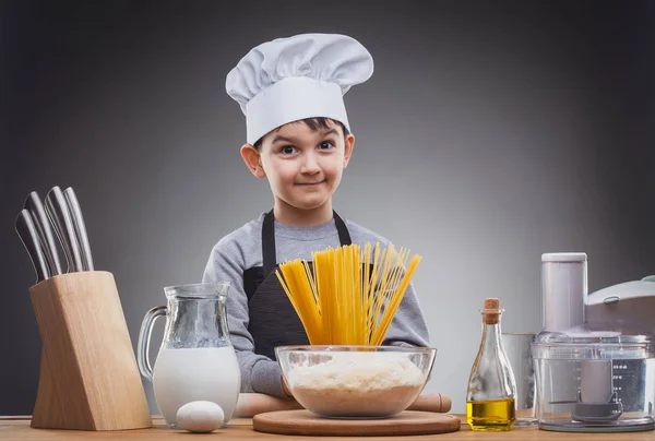 Jongen chef koken op een grijze achtergrond. — Stockfoto