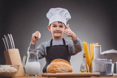 Gri bir arka planı olan aşçı çocuk..