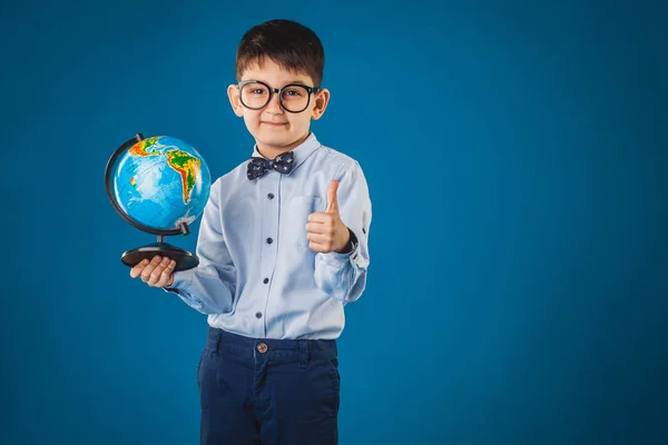 Leuke jongen met een globe op een blauwe achtergrond. — Stockfoto