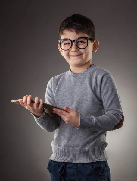 Cute boy z elektronicznej tabletki na szarym tle — Zdjęcie stockowe