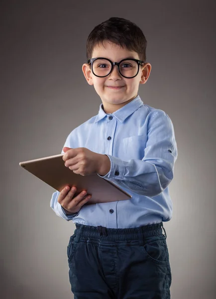 Симпатичный мальчик с электронным планшетом на сером фоне — стоковое фото
