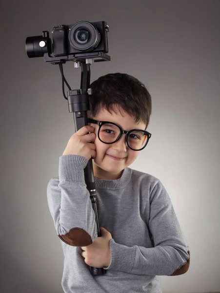 Netter Junge mit elektronischem Steadicam auf dem grauen Hintergrund — Stockfoto