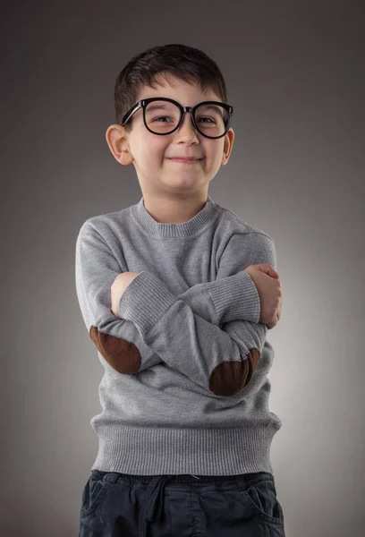 Bonito sorrindo menino em óculos no fundo cinza — Fotografia de Stock