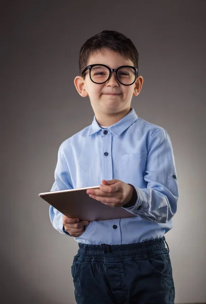 Cute boy with electronic tablet on the gray background — Stock Photo, Image