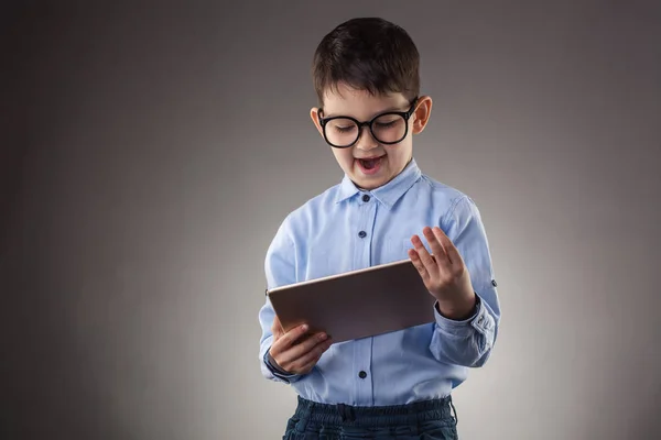 Söt pojke med elektronisk tablett på grå bakgrund — Stockfoto