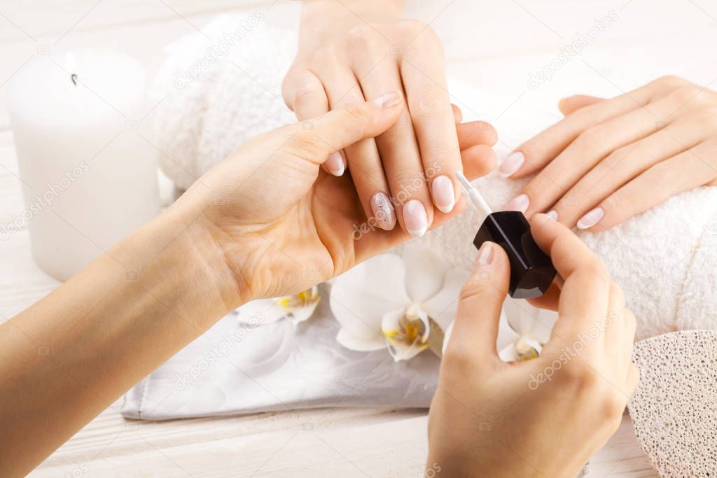 beautiful french manicure with orchid, candle and towel on the white wooden table. manicurist hands