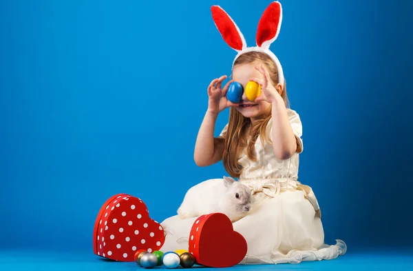 Niña linda con conejo blanco en cesta con huevos de Pascua. —  Fotos de Stock