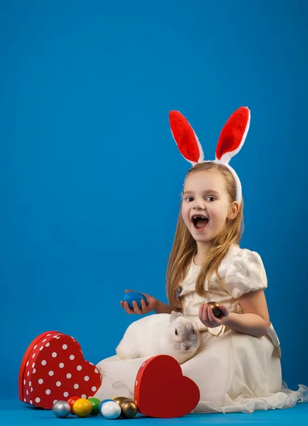 Niña linda con conejo blanco en cesta con huevos de Pascua. —  Fotos de Stock