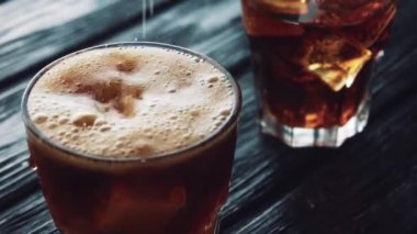 Kola, siyah ahşap bir masada buzlu bir bardağa dökülür..