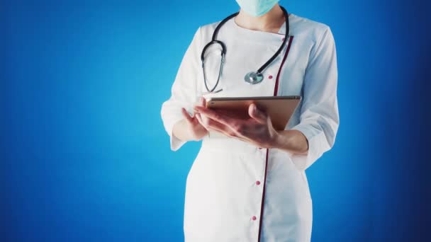 Femme médecin dans un manteau blanc et masque avec un stentoscope dans les mains. — Video