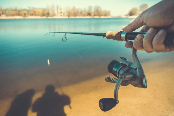 在湖上用钓竿钓鱼。男人的手与纺纱 — 图库照片