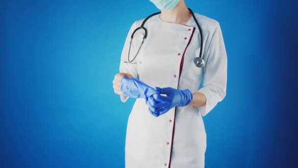 Medico femminile in un mantello bianco e maschera toglie i guanti sulle mani. — Video Stock