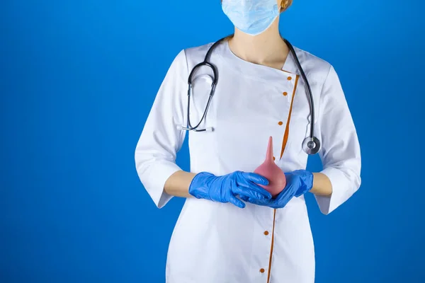 Enema na mão dos médicos sobre o fundo azul. — Fotografia de Stock