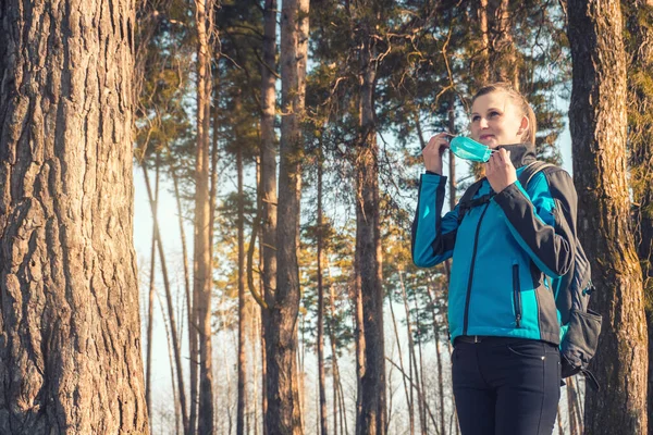 Jonge vrouw met medisch masker loopt in een lente dennenbos. Voorjaar. — Stockfoto