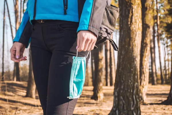 Young woman with medical mask walks in her hands. spring pinewood. — Stock Photo, Image