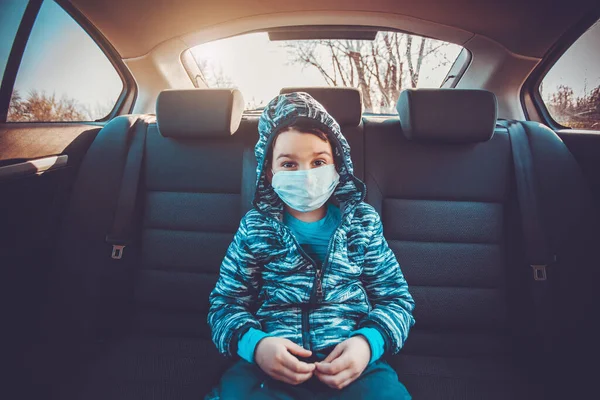 Ребенок в санитарной маске в машине для защиты коронного вируса или ковид-19 — стоковое фото