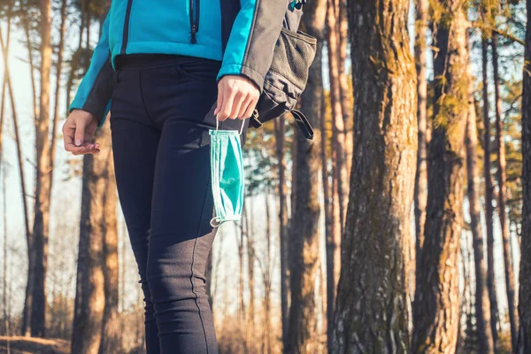 Young woman with medical mask walks in her hands. spring pinewood. — Stock Photo, Image