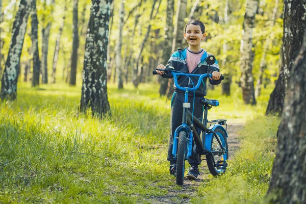 Happy kid passeios de ciclista na floresta em uma bicicleta de montanha . — Fotografia de Stock