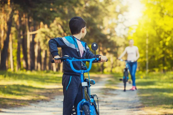 快乐的孩子骑自行车和妈妈骑自行车在阳光灿烂的森林里 — 图库照片