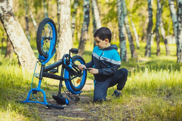 Kleine jongen fietser schudt een gebroken wiel op een fiets. — Stockfoto