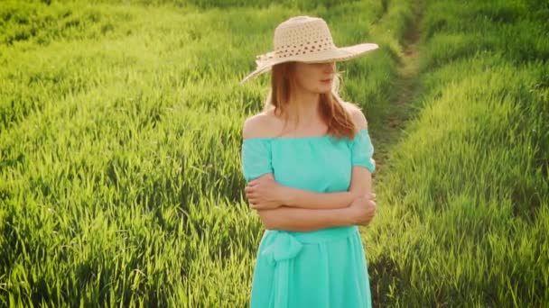 Молода жінка стоїть на пшеничному полі зі схід сонця на фоні — стокове відео