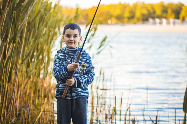 Bonito menino pega peixe em um lago de verão. — Fotografia de Stock