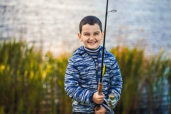 Netter Junge fängt Fische auf einem Sommersee. — Stockfoto