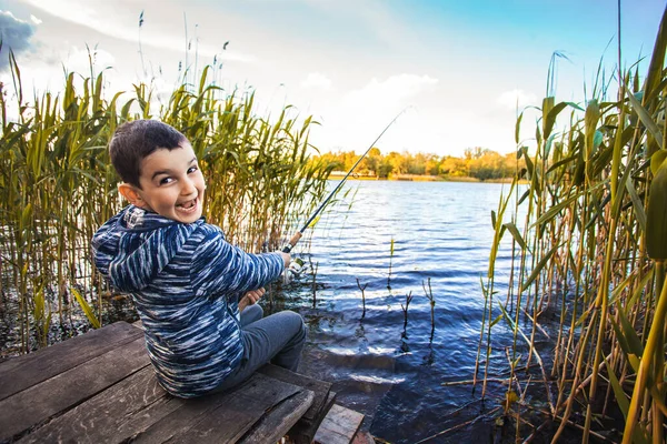 Mignon garçon capture des poissons sur un lac d'été. — Photo