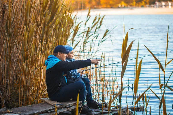 Lindo chico con papá atrapa peces en un lago de verano . —  Fotos de Stock
