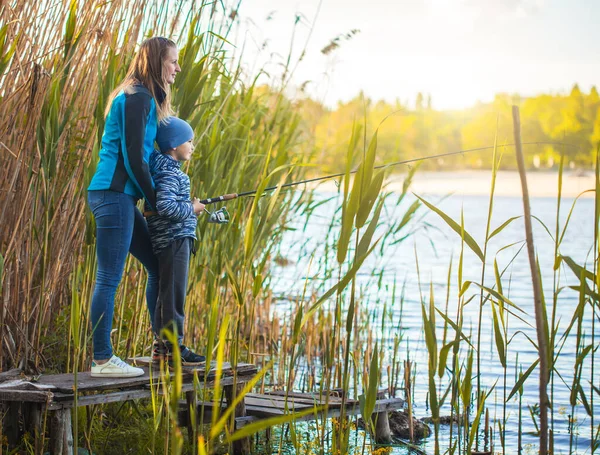 Lindo chico con mamá capturas de peces en un lago de verano . — Foto de Stock