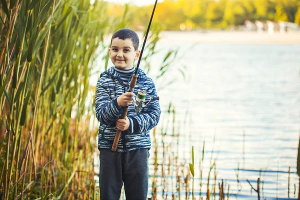 Lindo chico capturas de peces en un lago de verano. —  Fotos de Stock