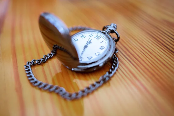 Silver pocket watch on a wood desk