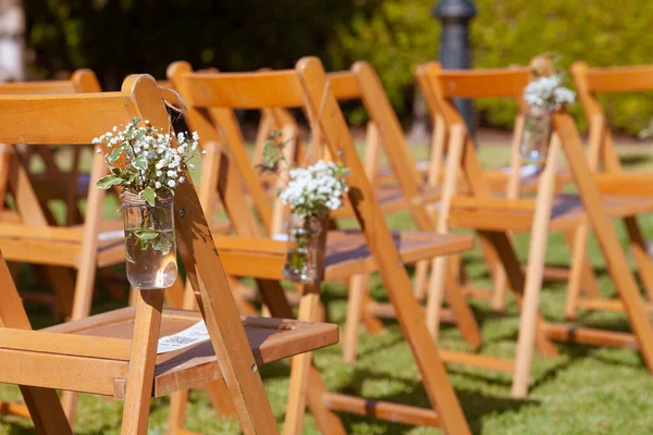 Floral arrangements on chairs at an outdoors wedding — Stock Photo, Image
