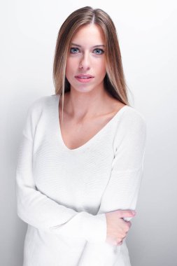 Utangaç bir kadın beyaz arka planda kameraya bakıyor.