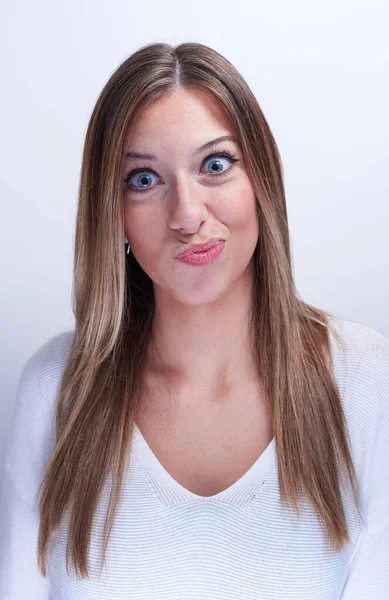 Young woman on a white background making funny faces — Stock Photo, Image