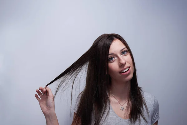 Retrato de uma mulher a tocar no cabelo como se estivesse danificada. — Fotografia de Stock