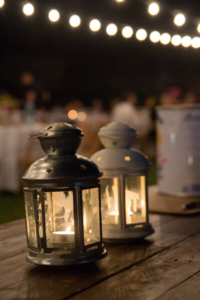 Lanterns on a wood table on an outdoors wedding banquet