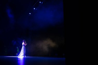 Tiyatronun arka sahnesindeki kadın şarkıcı.